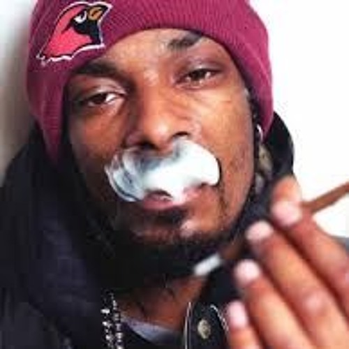 Close-up of a man in a red beanie exhaling smoke while holding a cigarette.
